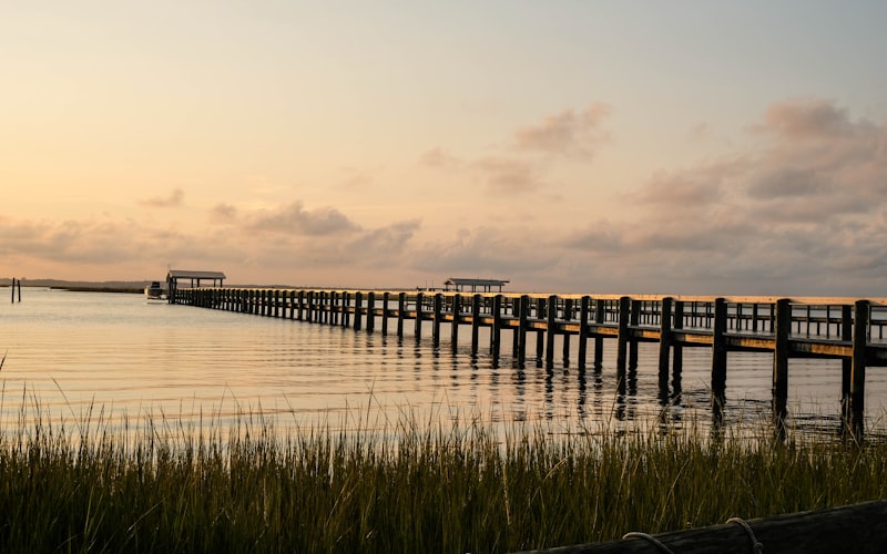 Wooden pier extending into the Chesapeake Bay at sunset with marsh grass