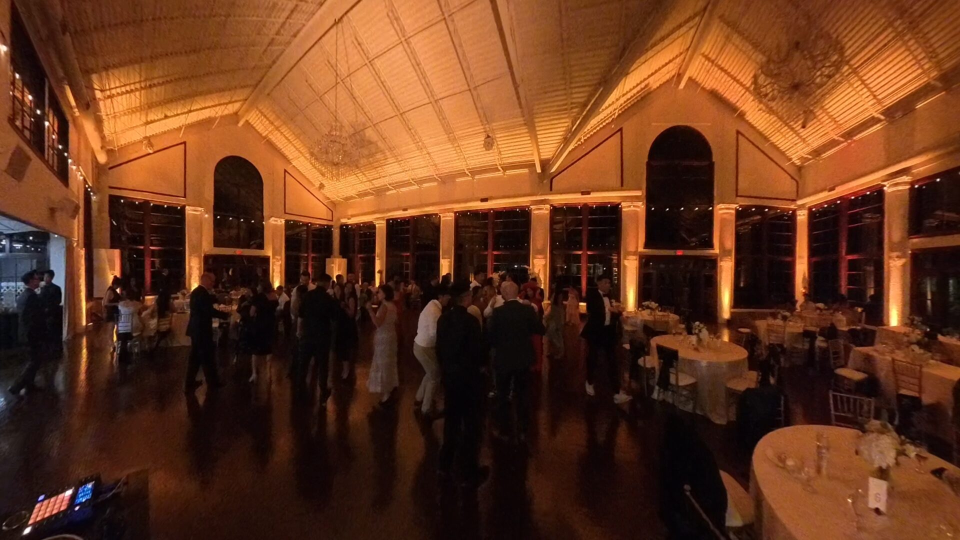 Same reception room later in the night with warm amber uplighting highlighting the walls and architecture