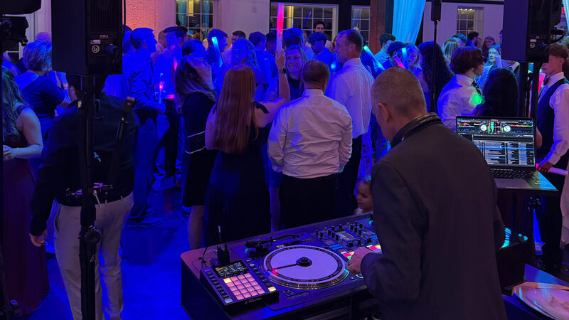Wedding dance floor with DJ performing and guests dancing under blue lighting
