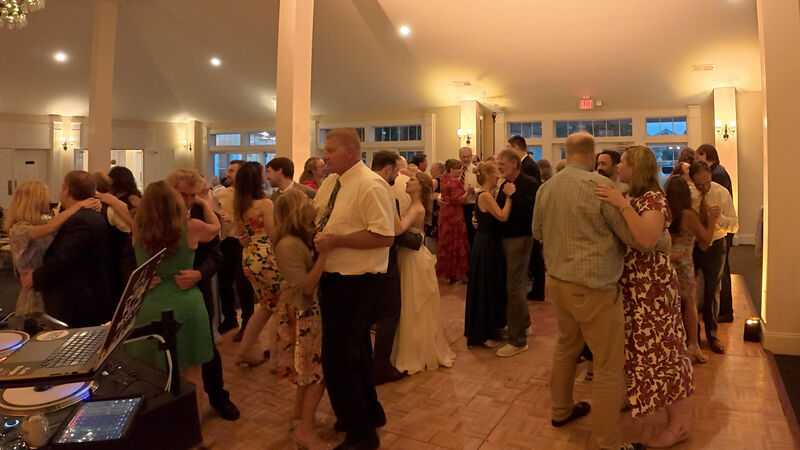 A couple slow dancing at a wedding reception under warm lighting