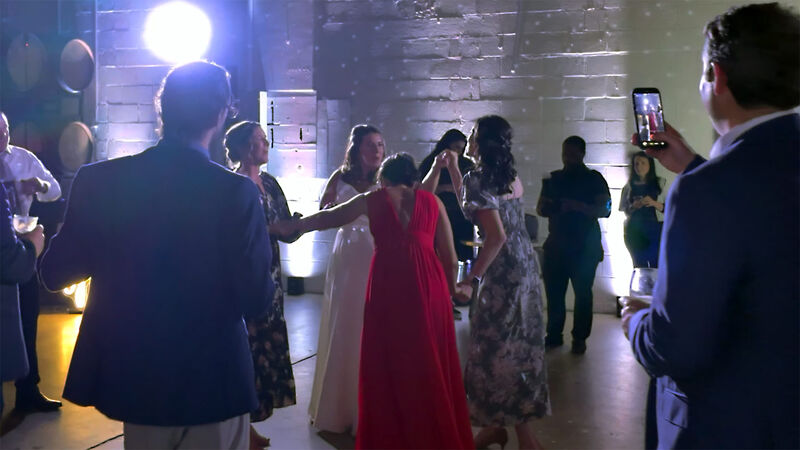 Guests dancing at a wedding reception while someone records on a phone