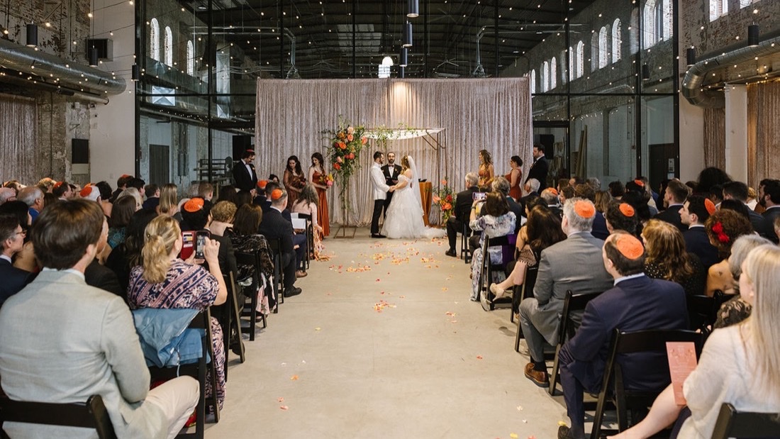 Wedding ceremony inside The Butterfly Room with string lights and industrial brick architecture